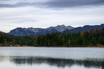 Calm alpine lake with forest and mountain ridge