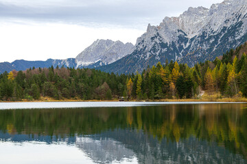 Calm alpine lake with forest and rocky mountains