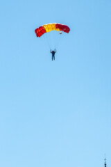 Parachutists glide down into the parade square displaying the national spanish flag.