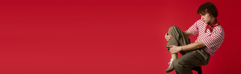 Obraz premium Teenager showcases dynamic fashion flair against vibrant red backdrop with playful pose