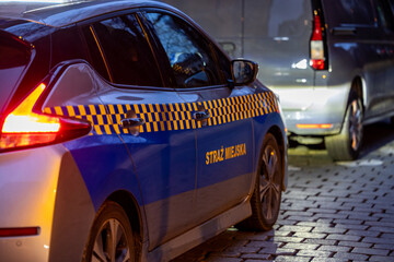 Straż miejska wieczorem, podczas służby z pojazdem w mieście kontrola © FotoDax