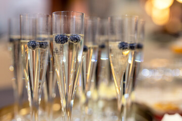 Glasses of white champagne with blueberry on a table at a celebration. Happy new year and merry christmas