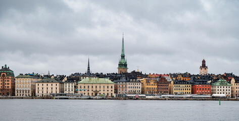Fototapeta premium Panoramic view of Stockholm cityscape with colorful historic buildings and cloudy sky across the water