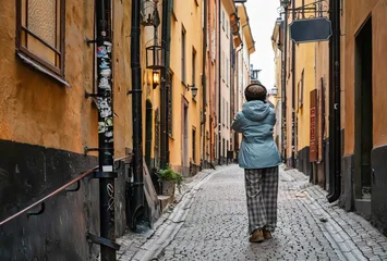 Fototapeten Enge Straßen Tourist exploring the narrow cobblestone streets of Gamla Stan in Stockholm during winter, admiring traditional Scandinavian architecture on a peaceful solo walk  © C&A