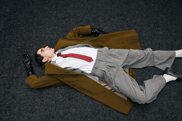 Handsome man in stylish fashion poses dramatically on the floor of a chic indoor setting
