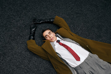 Stylish man lying on dark floor in elegant attire full of confidence and charm