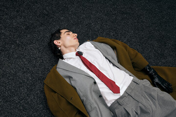 Stylish man poses effortlessly on the floor in a modern indoor setting