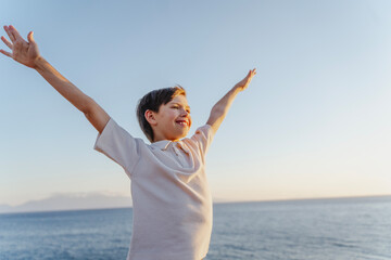 Cute Caucasian boy 10 years old standing on the seashore at sunset, dreams about the future concept © olezzo