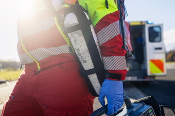 Emergency medical service. Paramedic hand in blue surgical gloves while running with defibrillator monitor and other equipment against ambulance car. Themes rescue, urgency and health care.