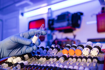 Close-up of paramedic hands holding ampoule with medication in ambulance car of emergency medical service.