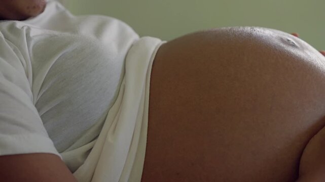 Side view of pregnant woman s belly showing natural skin and wearing soft maternity clothes, representing pregnancy and prenatal care.