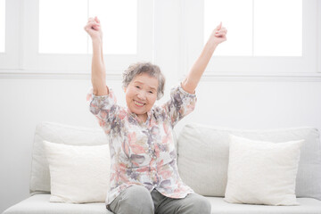 An elderly woman energetically raising both hands in a victory pose Evoking images of health, refreshing stretches, and a sense of well-being