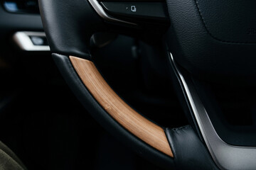 A premium, modern brown car interior, leather steering wheel, large navigation screen, air ducts, deflectors on the car panel. Interior details.
