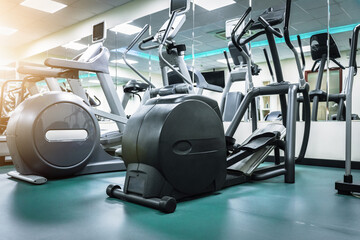 Gym equipment arranged in a modern fitness center with exercise machines and mirrors
