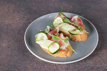 Sandwiches with cream cheese, jamon and cucumber on gray plate
