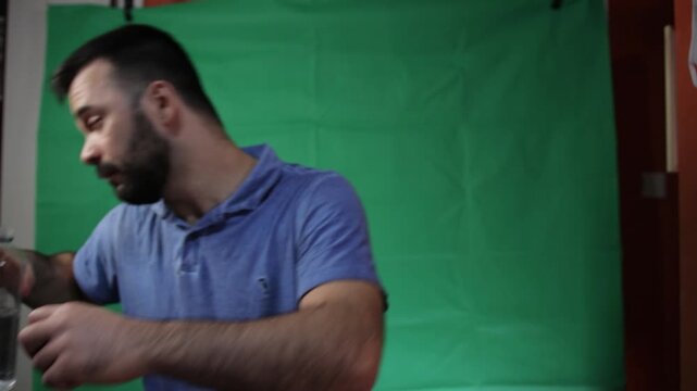 Close up of a man holding a transparent bottle on a green screen.