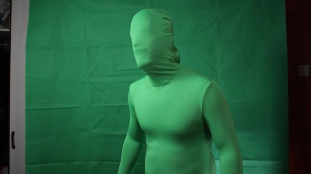 Actor in a full green body suit making movements for motion capture.