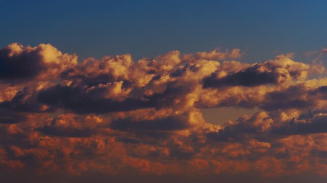 夕焼けに染まる燃えるようなオレンジ色の雲と青い空のコントラスト タイムラプス