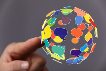 Abstract image of a hand holding a sphere of speech bubbles symbolizing global communication, connection, and social networking. Concept of digi
