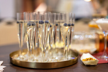 Glasses of white champagne with blueberry on a table at a celebration. Happy new year and merry christmas