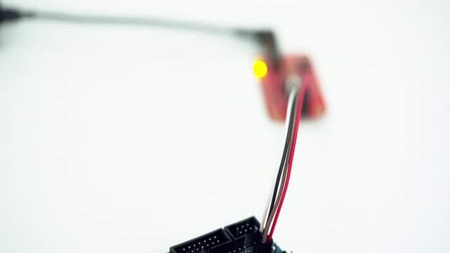 A blue electronic device with a white label. The device is plugged into a white surface