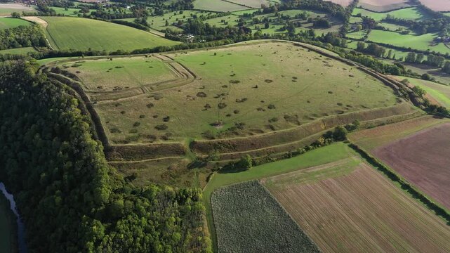 E over Hod Hill Iron Age hillfort. Blackmore Vale, Dorset. Main rampart dates from 500 BC. Once home of the Durotriges. Later Roman fort in NW corner. Video fly down in to Roman fort