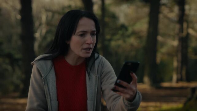  a young woman hiking in a forest as she video calls with her smartphone. With a bright smile and a backpack, she captures the moment amidst the natural scenery, reflecting the joy 