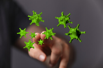 Digitally created 3D green coronavirus cells approaching a human finger. Concept of pandemic, health, medical,
