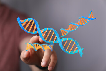 Close-up of a hand holding and interacting with floating DNA strands symbolizing genetics and...