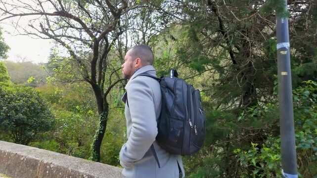 Man with backpack walking through green park area
Traveler exploring a park surrounded by trees and natural environment in a peaceful setting.