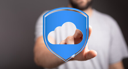 Hand pointing at a cloud icon within a shield representing data protection, cybersecurity and secure informatio
