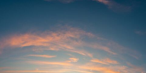 The dawn sky unveils beautiful colors as clouds drift gently across the blue horizon