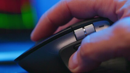 Closeup of a hand clicking a computer mouse on a desk, shallow depth of field with colorful ambient lighting and soft bokeh, workspace concept for technology, productivity, and online use.