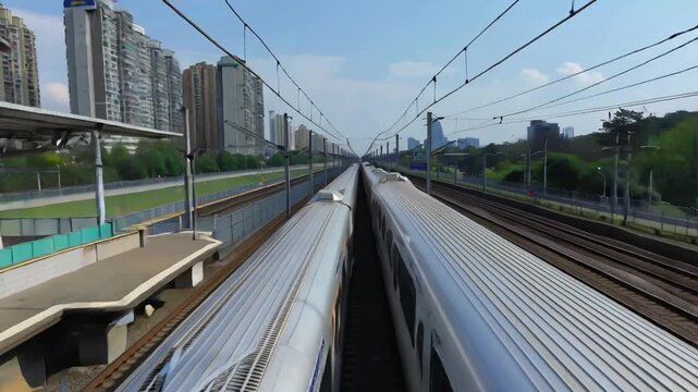 Sleek high-speed trains parallel on tracks, urban landscape with modern buildings and overhead wires