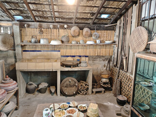 Rustic vintage kitchen room featuring bamboo wall and traditional wooden shelf with earthenware pottery and woven basket showing simple rural lifestyle and cultural nostalgia inside asian home
