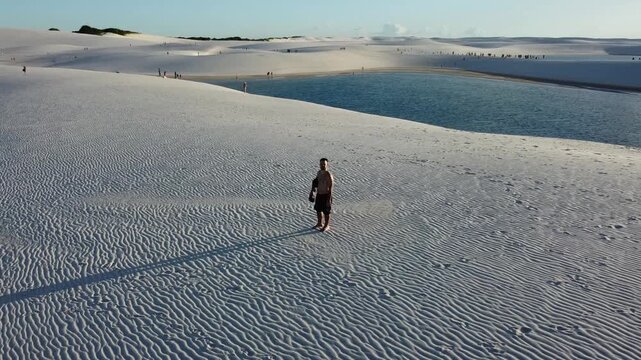 Lone man standing on top of a sand dune.