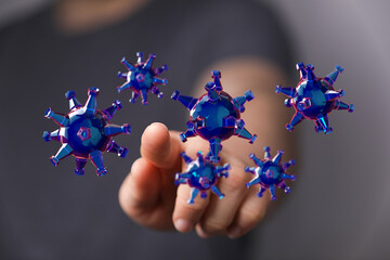 Close up of person's finger touching digitally created Coronavirus particles, representing concept of disease