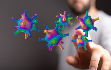 Artistic rendering of multicolored coronavirus model being touched by a human hand, illustrating concepts of s