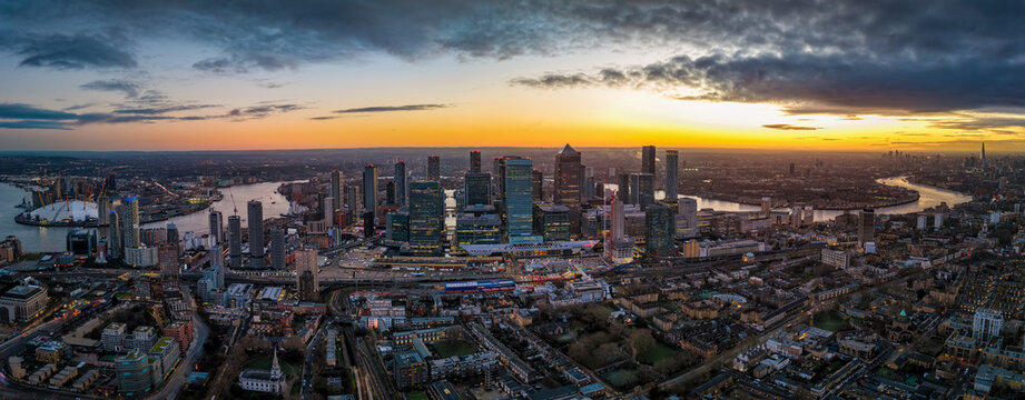 Panoramic aerial view of the iilluminated skyline of London, England, stretching from Greenwich over Canary Wharf along river Thames until Tower Bridge and the City during dusk