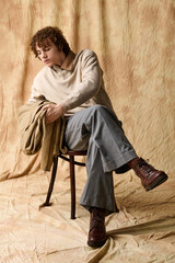 Naklejka premium Stylish teenager in casual fashion poses elegantly on a wooden chair