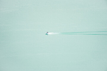 Motorboat moving across a turquoise water surface.
