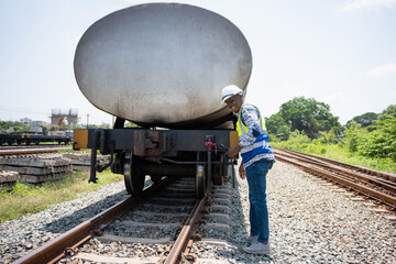 Worker man examining railway tanker at rail yard, Railway maintenance worker inspecting freight...