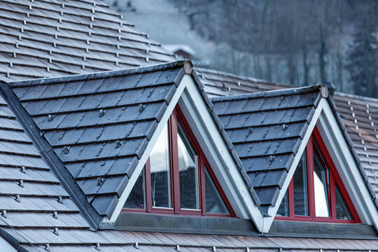 Close-up of a building's roof with triangle windows. Modern architecture with a dark, textured rooft