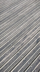 High angle view of a grey wooden terrace floor with rhythmic diagonal planks and metal screws