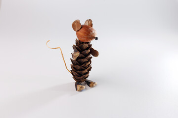 Naklejka premium handmade forest mouse figurine made of pine cone hazelnut wood scales twine isolated on white background. eco friendly diy nature craft for kids school education creative autumn hobby workshop,