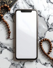 Overhead view of a smartphone with a blank screen rests on a marbled surface beside prayer beads and an open book