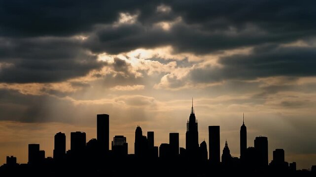 A silhouette of a cityscape set against a dramatic sky. The clouds obscure light, while golden rays break through
