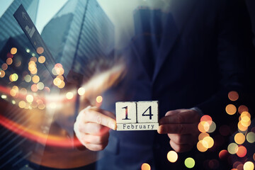 A businessman in a suit holds wooden cubes in his hand since February 14th. Valentine's day concept. double exposure skyscraper