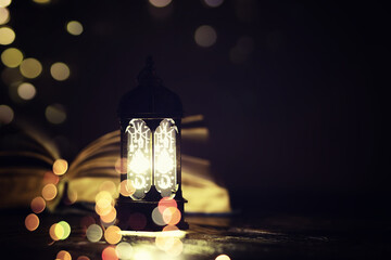 Ramadan Kareem background. Ornamental Arabic lantern glowing and the holy book of Quran.