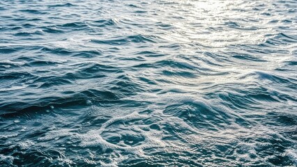 Obraz premium Gentle ocean waves shimmering in sunlight on a calm sea surface